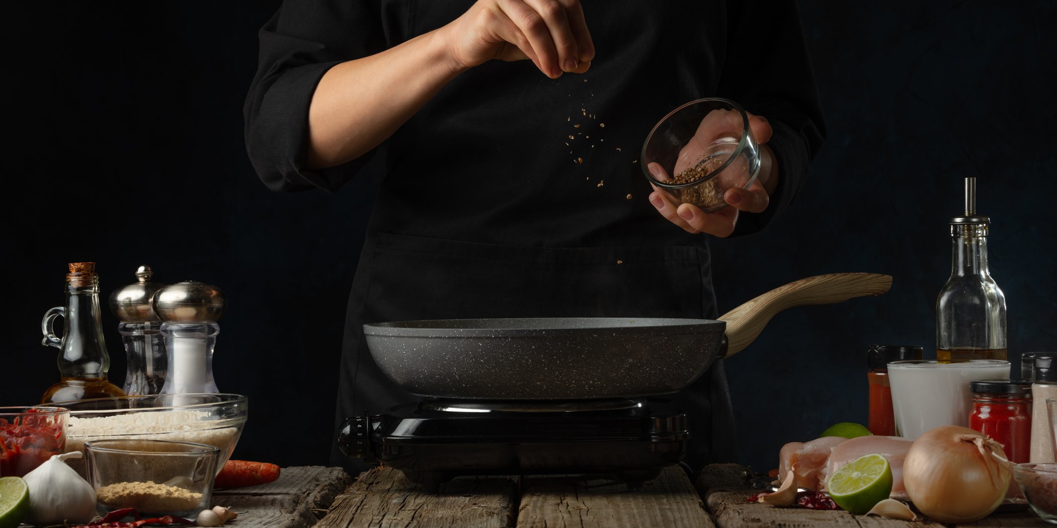 Aneke adding seasoning to a steak being cooked on a hob and rustic worktop