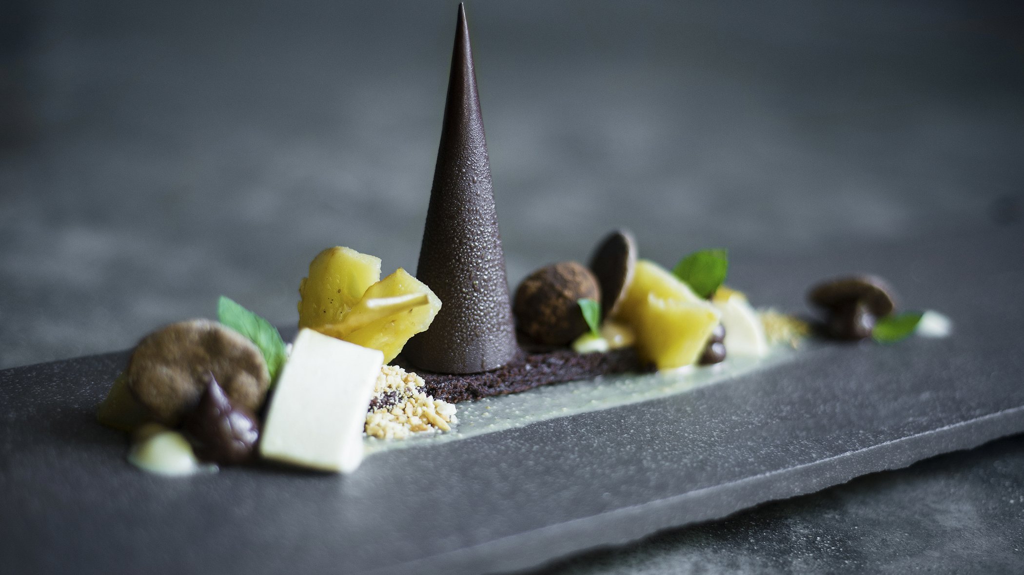 High-end beautifully prepared chocolate pyramid with lemon sorbet, mint and chocolate truffle served on a decorative slab of marble