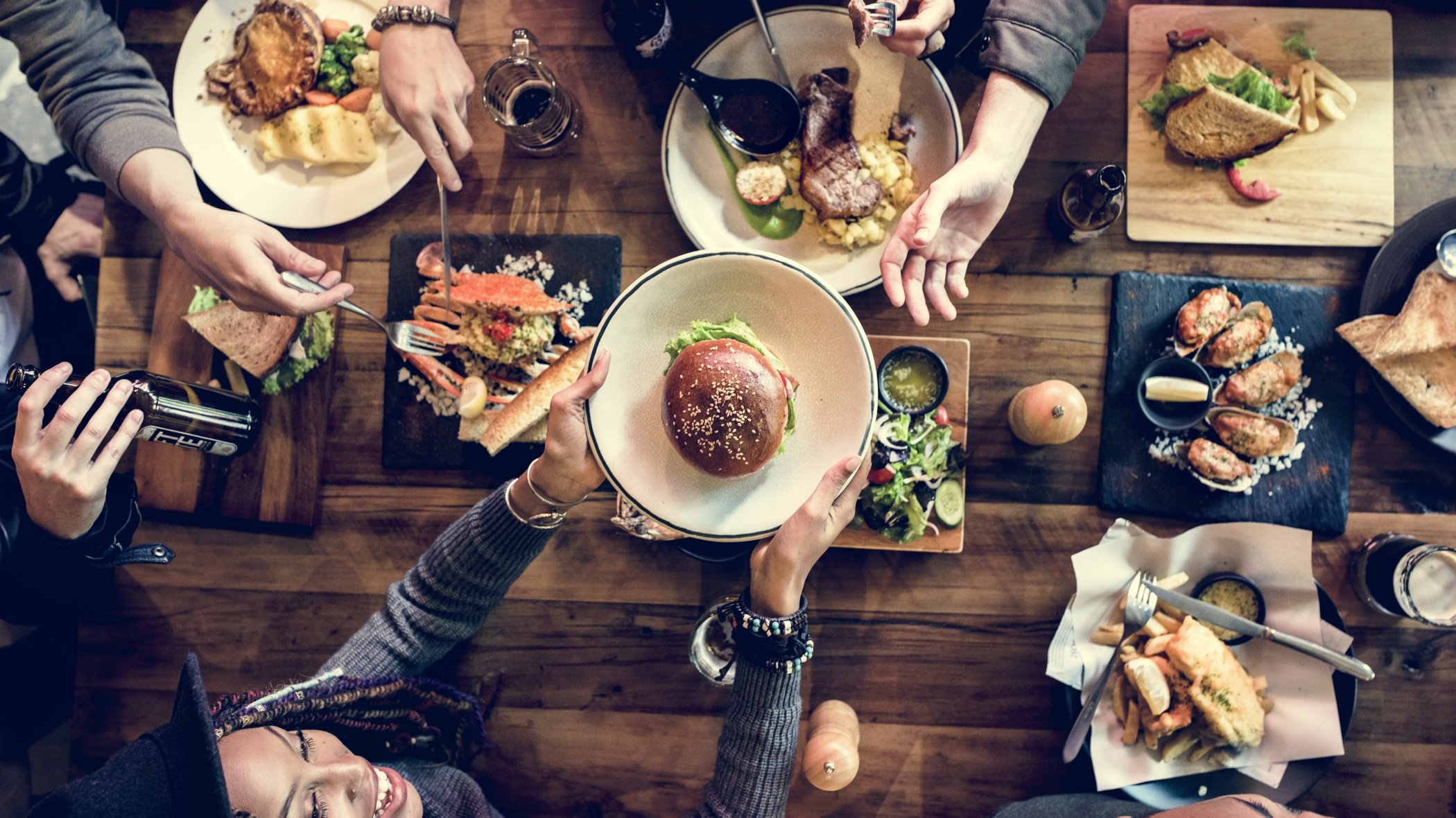 Rustic table surrounded with casual diners enjoying a selection of freshly prepared cuisine