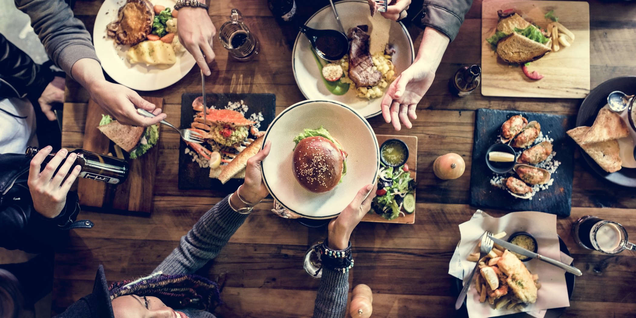 Rustic table surrounded with casual diners enjoying a selection of freshly prepared cuisine