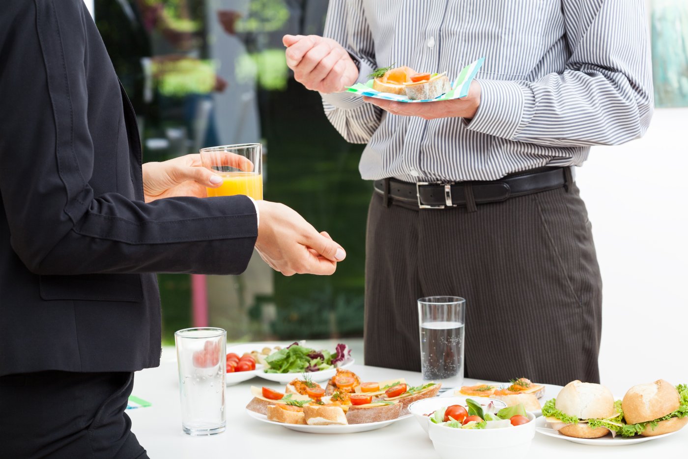 Two businessmen talking over a buffet table featuring a selection of fine finger food