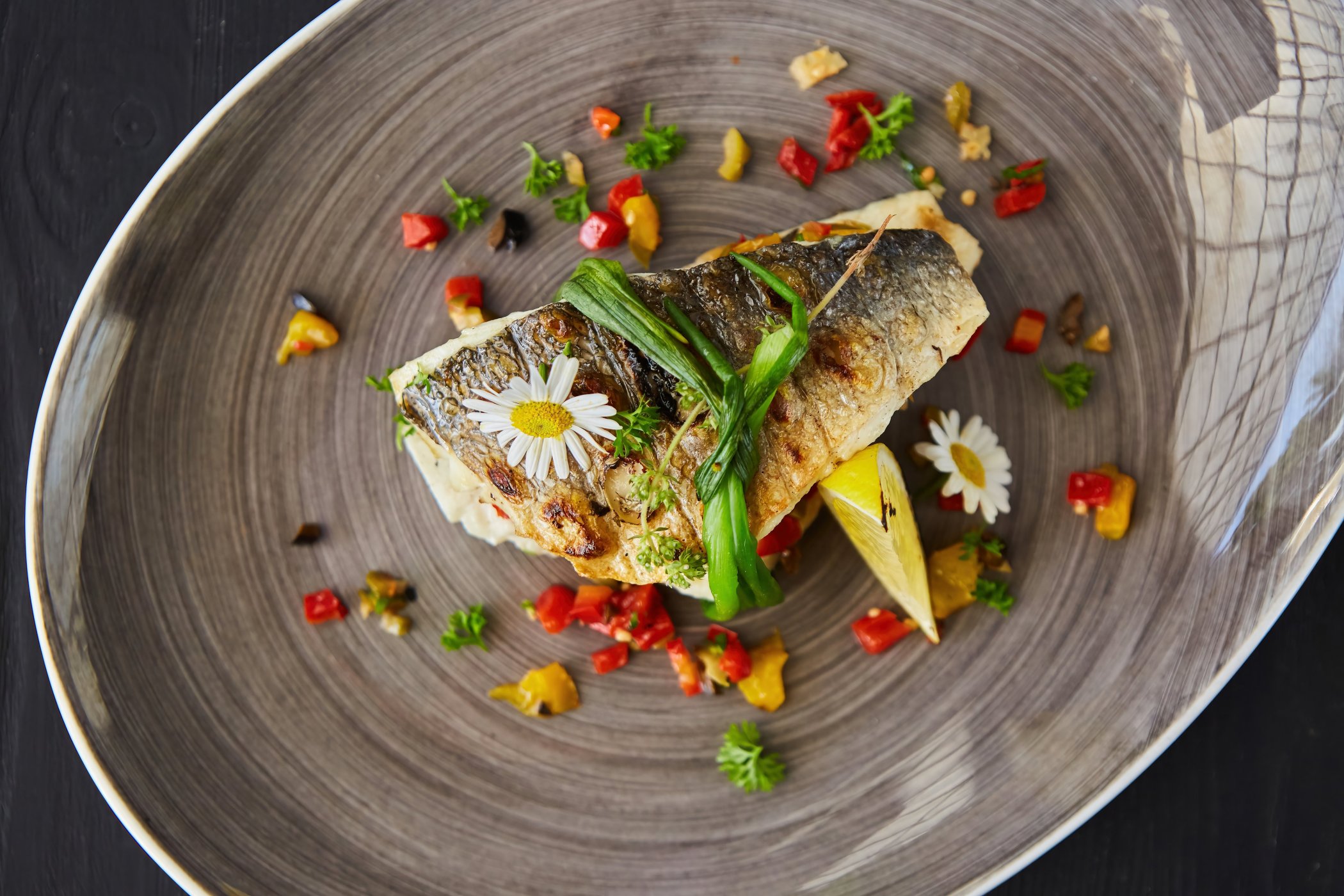 Delicious tuna steak decorated with vegetables and served on a beautiful grey swirled plate