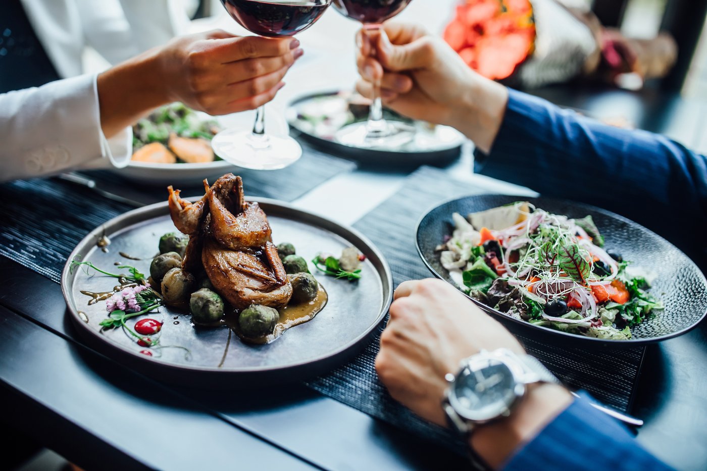 Succulent duck dishes served to diners with salad and wine on a contemporary black table