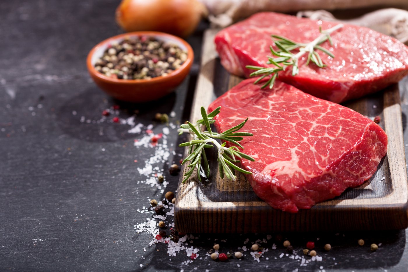 Beautifully presented uncooked rump steak with a sprig of thyme and covered with sea salt resting on a wooden chopping board