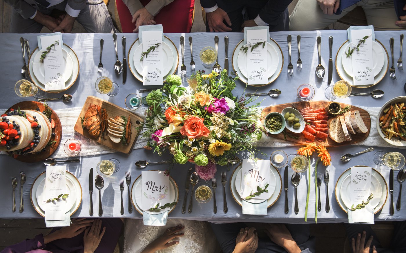 A beautifully dressed dining table ready for a wedding with plates, bread and olive platter and cake