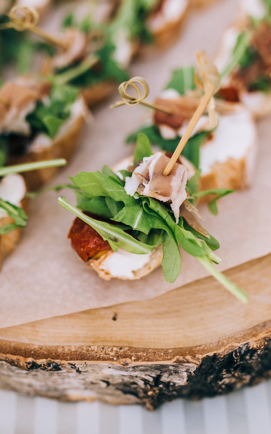Parma ham, rocket and scallop skewers presented on a rustic sawn tree stump