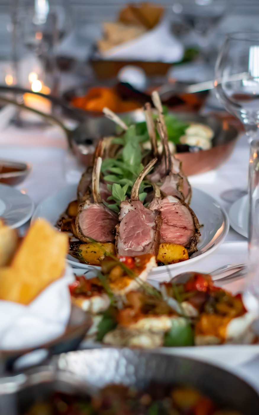 Succulent lamb chops with bone resented alongside vegetables in a gold trimmed white bowl