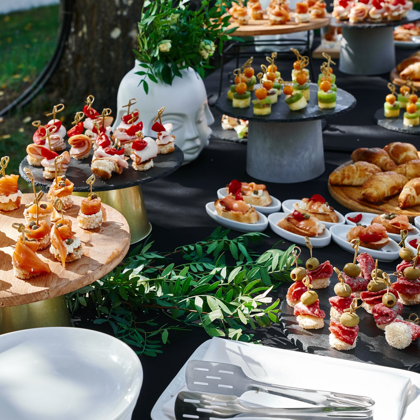 A large dining table set in a rustic garden with a delicious savoury buffet spread, napkins and cutlery