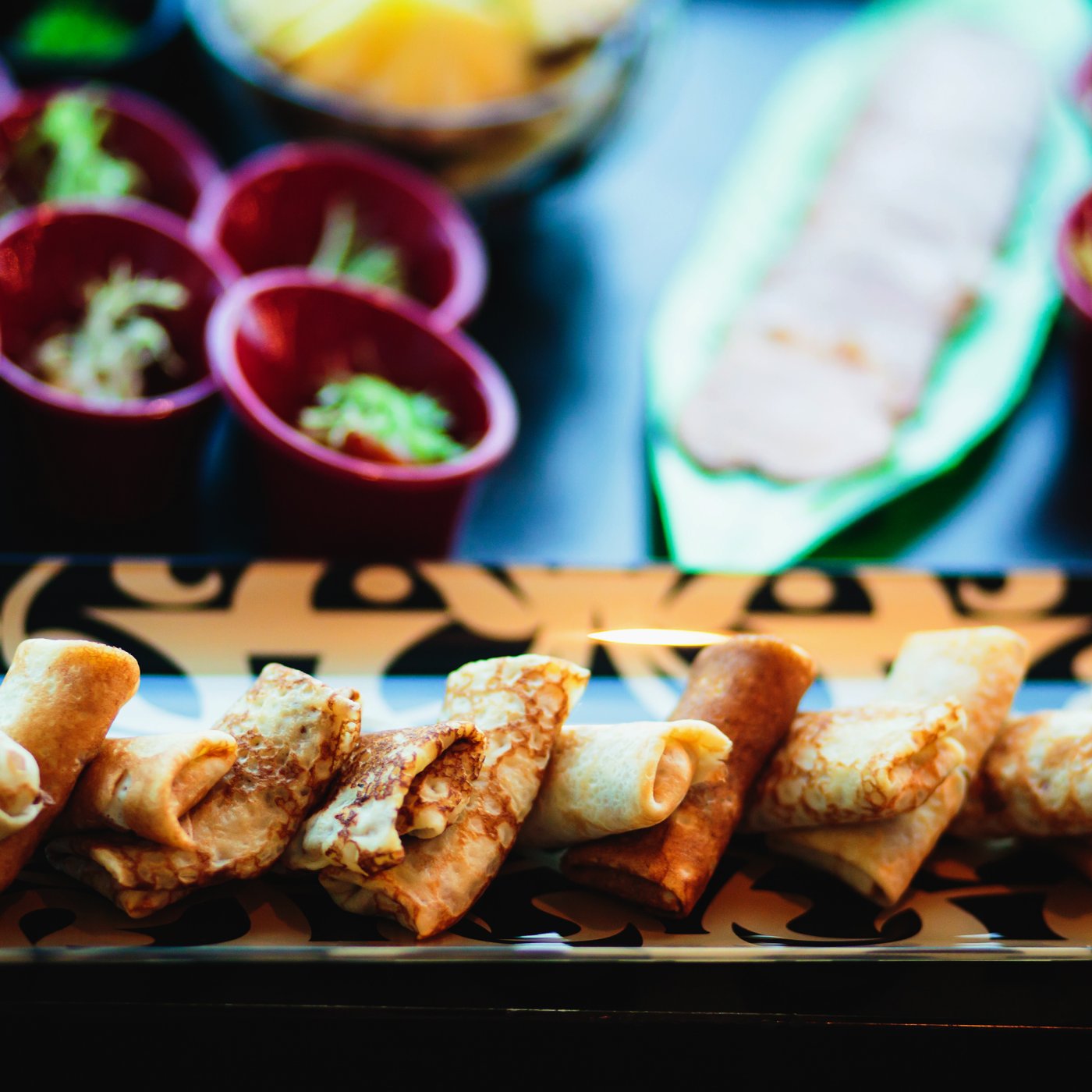 Beautifully presented samosas on a wooden batten with dark wood backdrop and complimentary salads