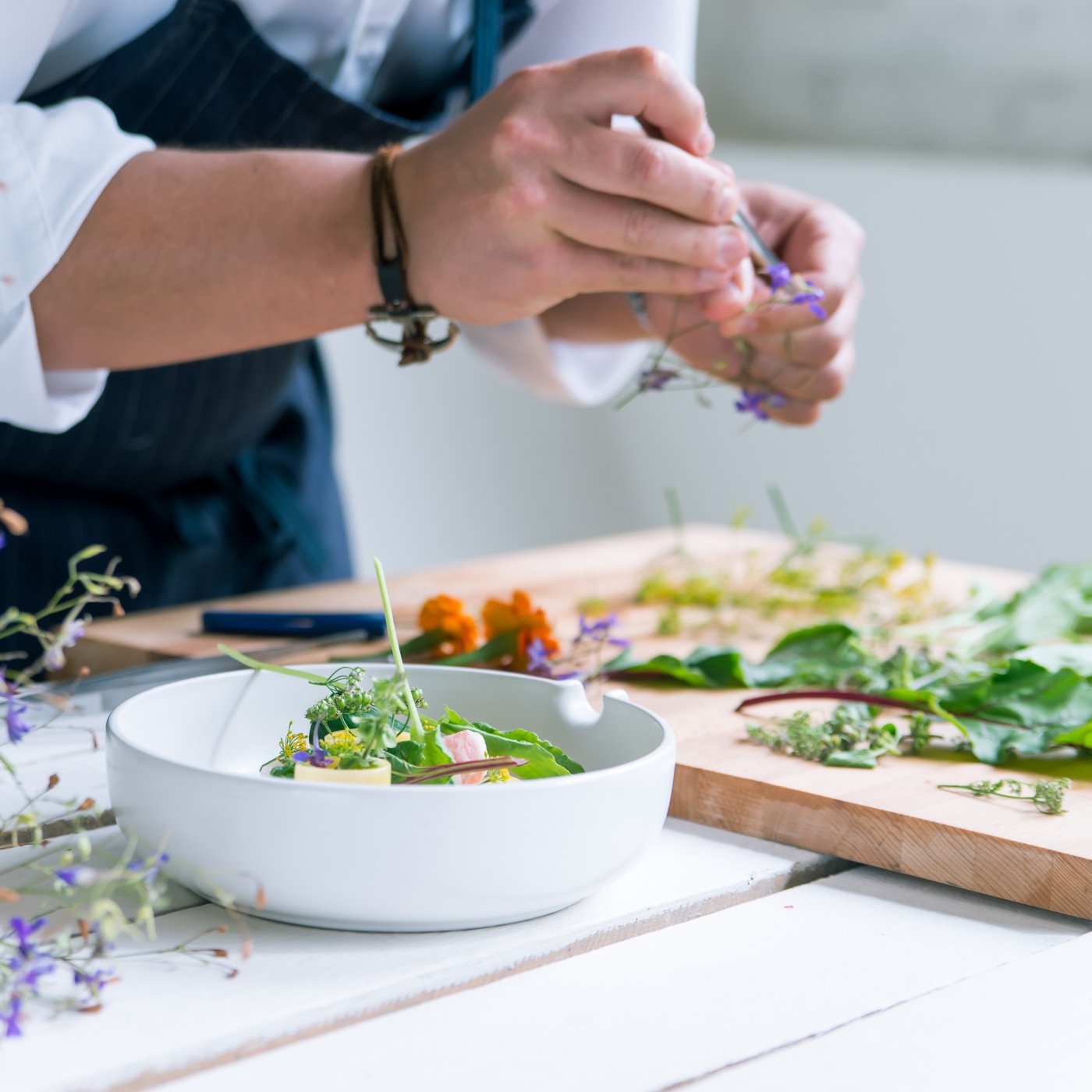 A beginner dresses a salad in a white bowl