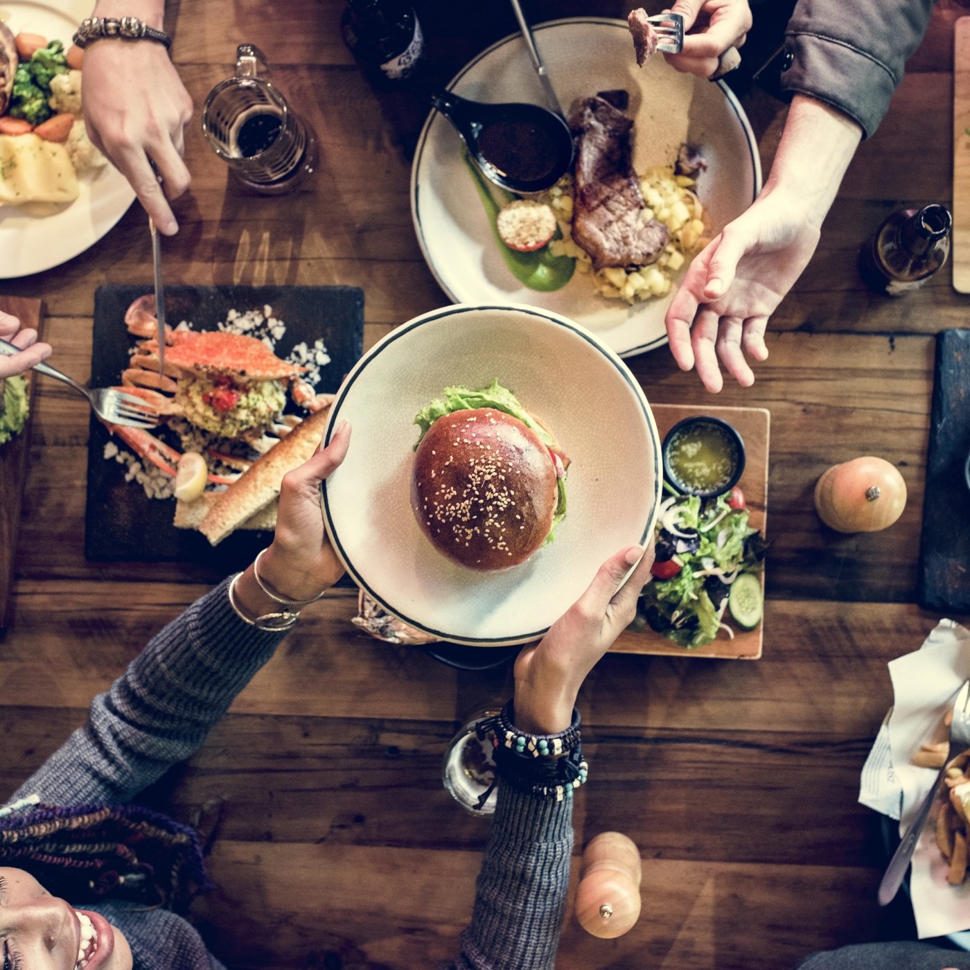 Rustic table surrounded with casual diners enjoying a selection of freshly prepared cuisine