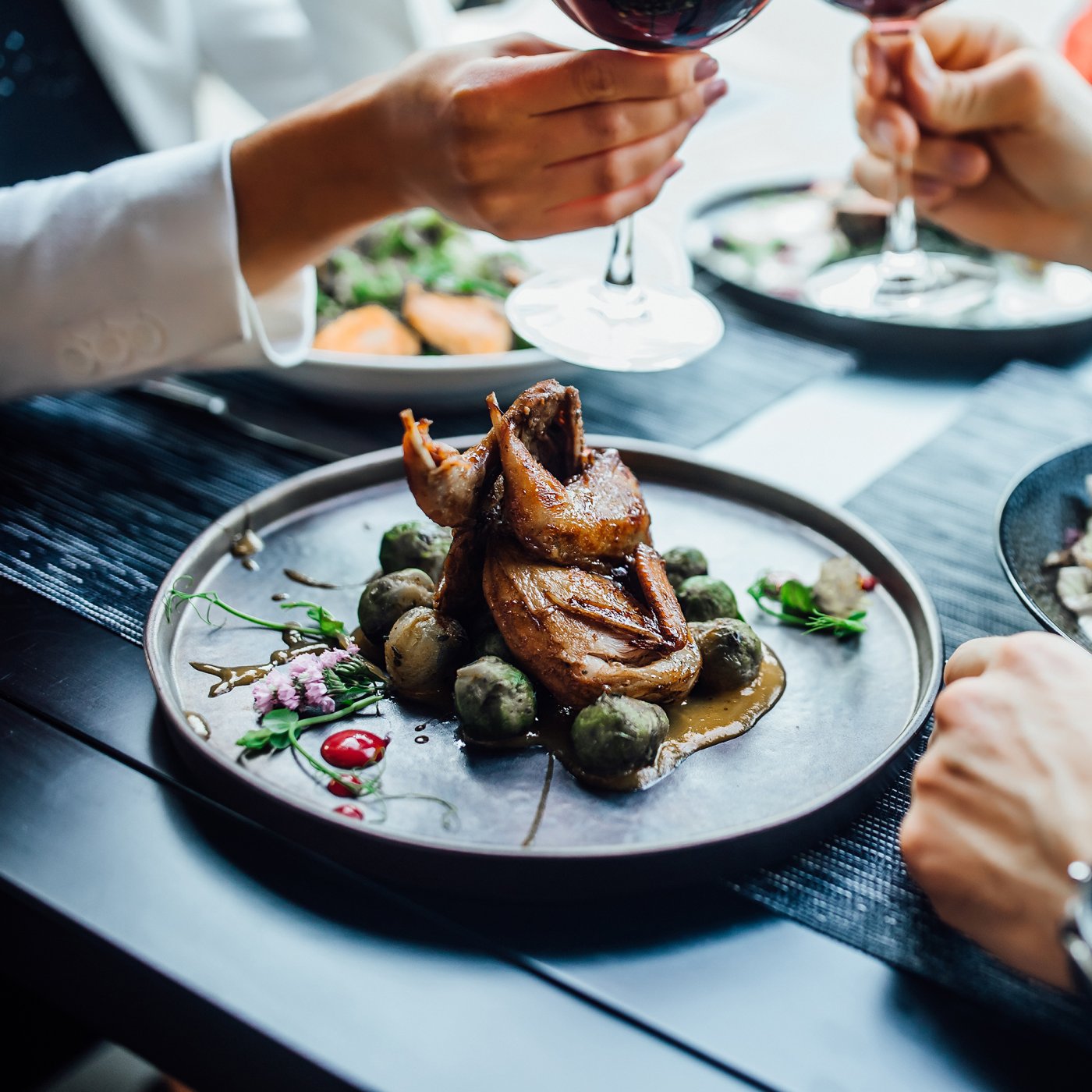 Succulent duck dishes served to diners with salad and wine on a contemporary black table