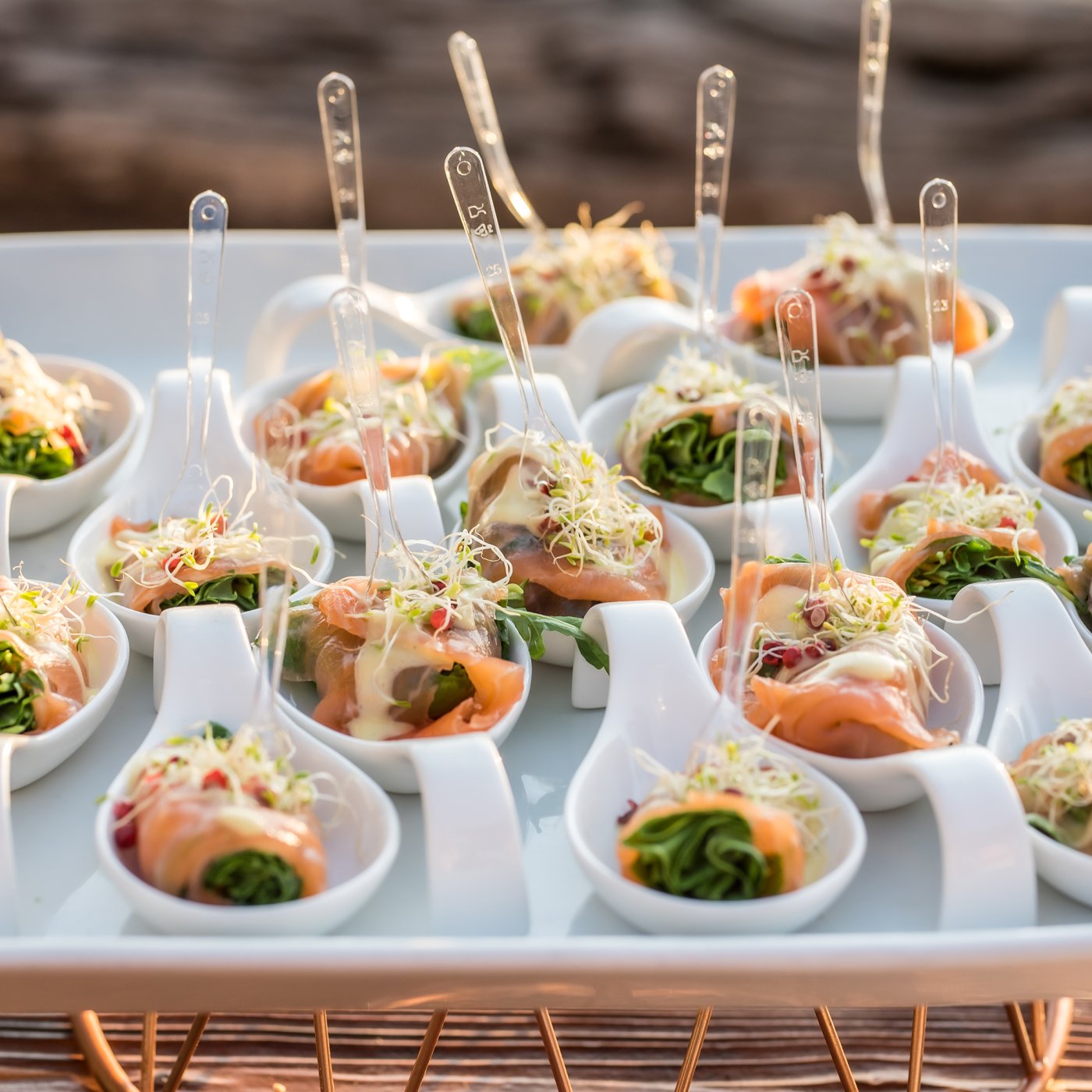 Small saucers carefully positioned on a serving tray containing smoked salmon dressed with salad appertisers
