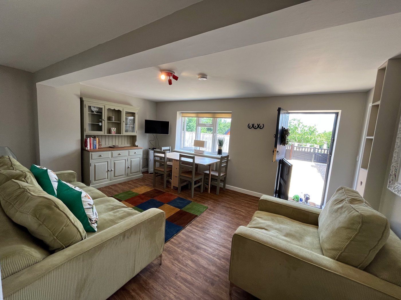 Wide shot of lounge, two large armchairs in green, oak floor and nice views into fields